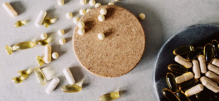 Different types of pills on a white table and in a bowl.