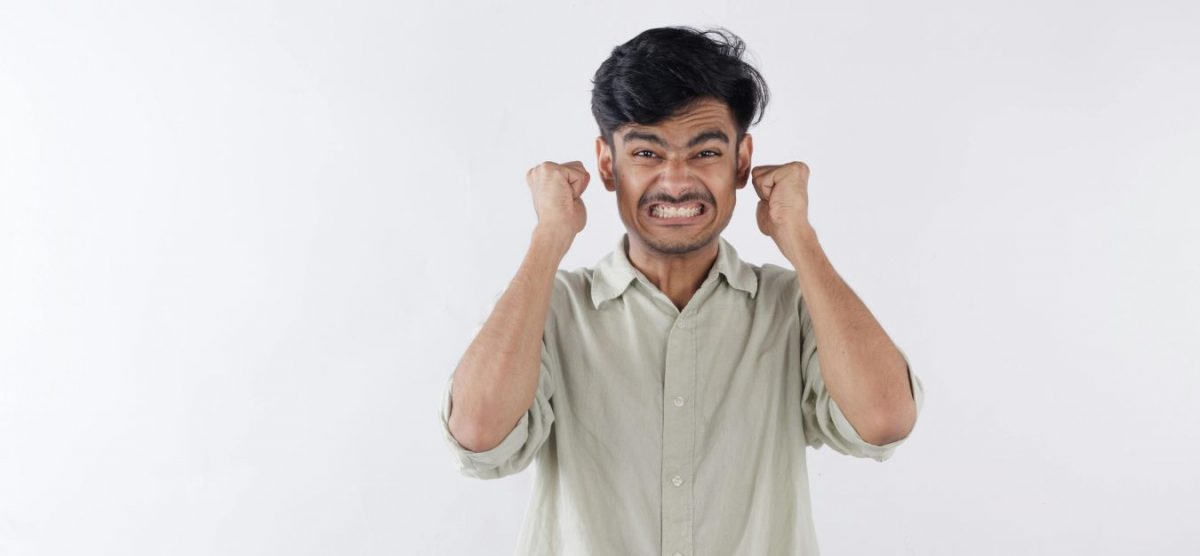 A man clenching his jaw, with both hands at the sides of his head.